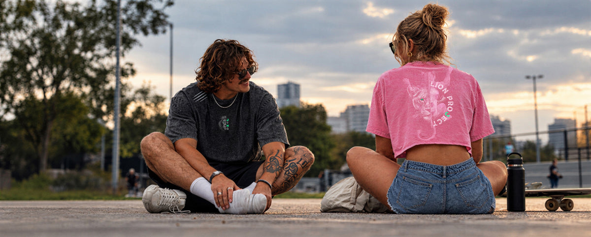 Couple en t-shirts JUSTHANG Lion Project assis dans un skatepark au coucher du soleil